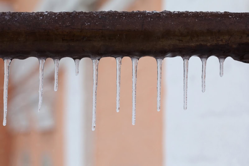 What Should I Do About Frozen Pipes? Icicles hanging from a brown pipe.