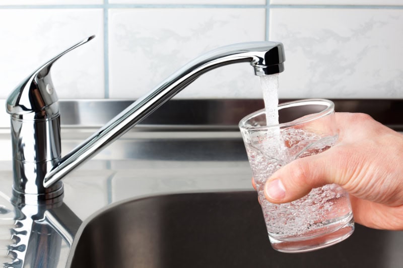 5 Benefits of a Plumbing Maintenance Plan. A cup is filling up with water under a kitchen sink faucet