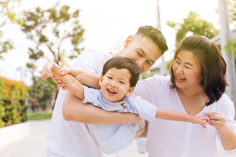 Improve Your Drinking Water Today. Image is a photograph of a family having fun and carrying a child in public park.